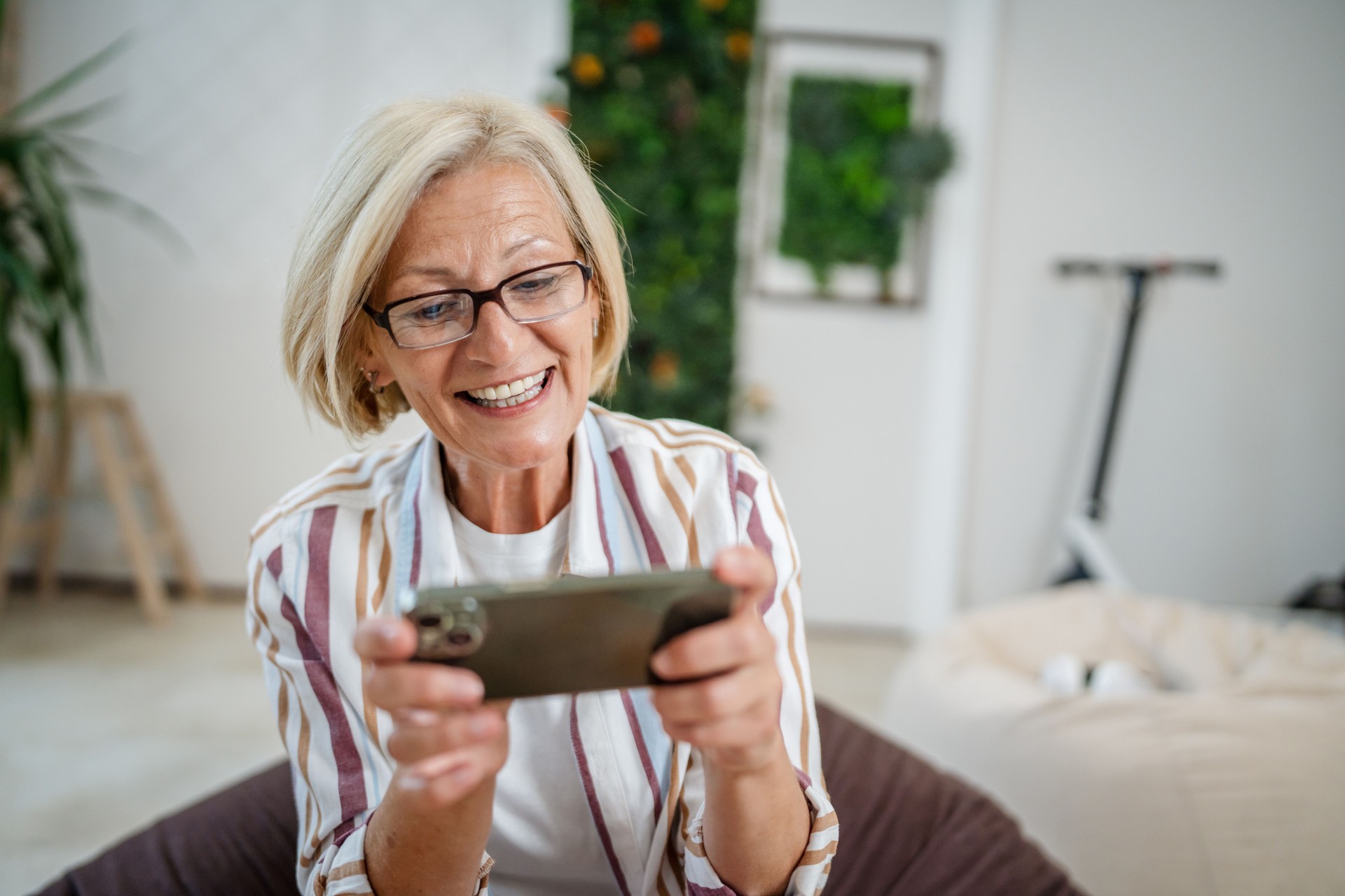 Mature woman use mobile smart phone play video games sit indoor