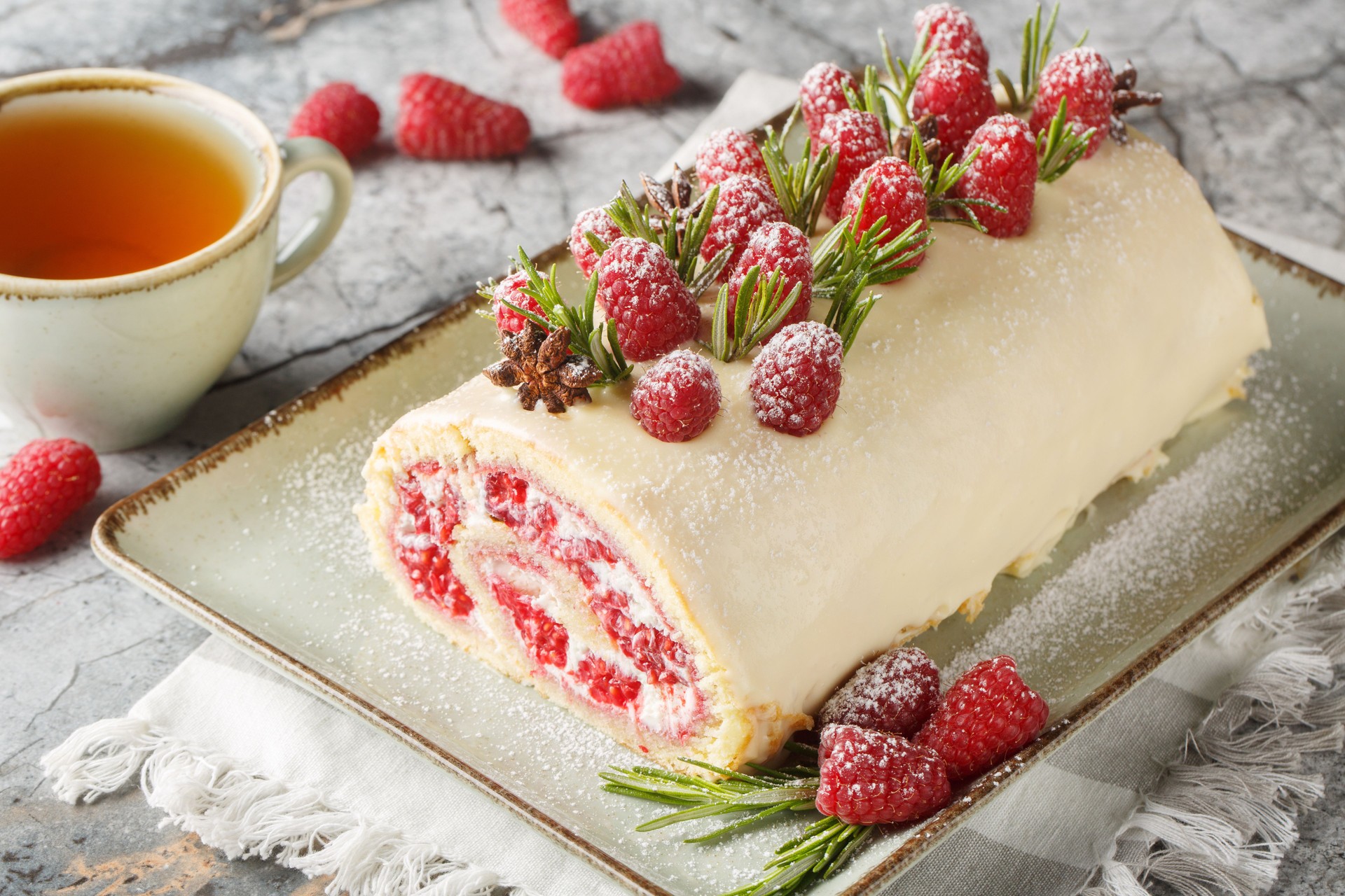 Raspberry sponge roll with jam, fresh berries, cream cheese covered with white chocolate close-up in a plate. Horizontal